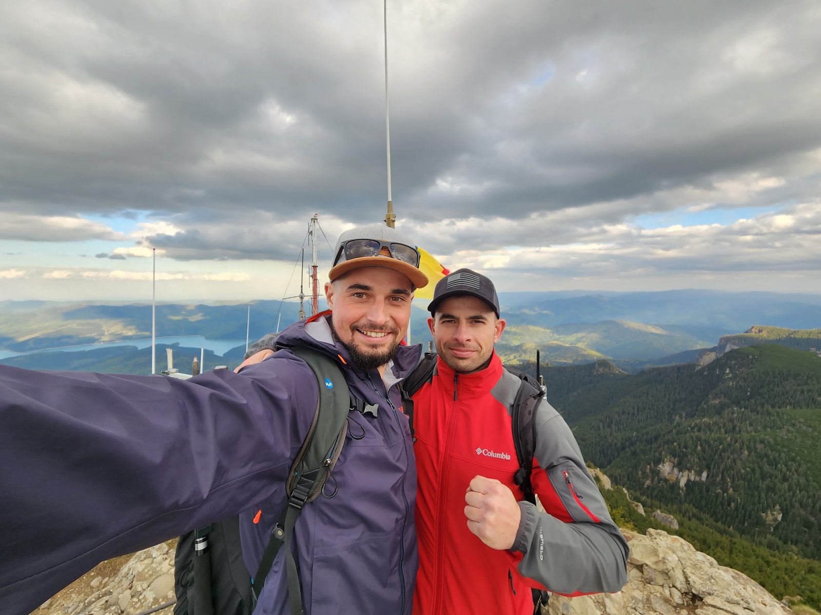 Emanuel and his brother on a summit in Romania with the Romanian flag behind them