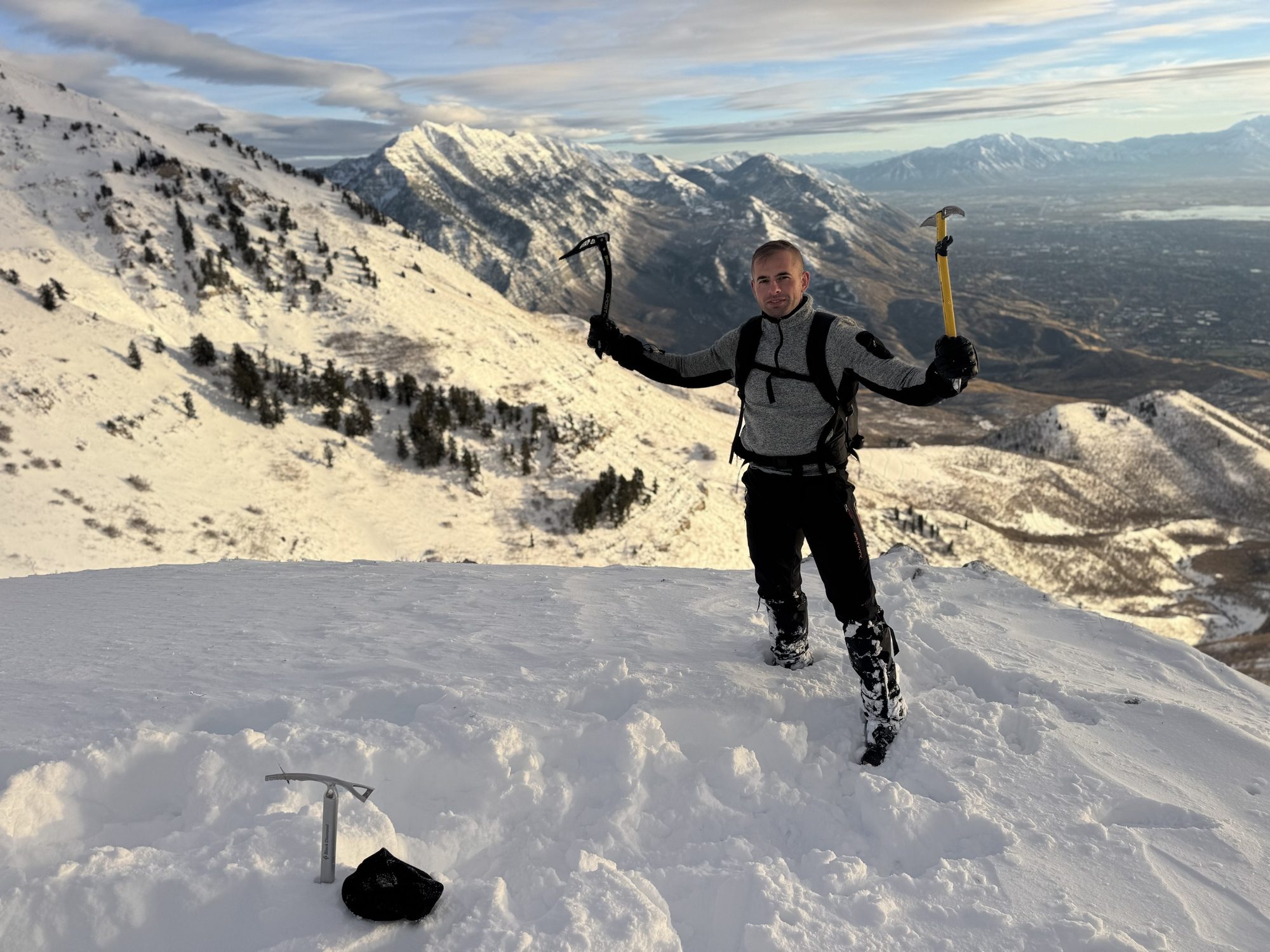 Emanuel Balmus on a snow covered summit above the Salt Lake Valley at sunrise